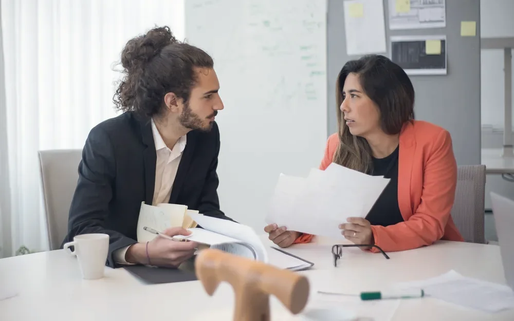 Two business partners in a focused conversation across a desk